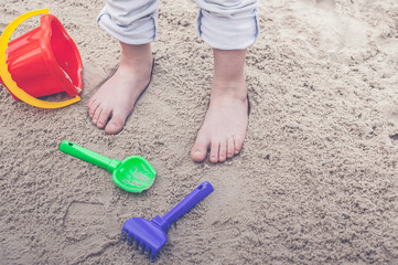 Fototapeta na wymiar Children's feet in the sand and sandboxing equipment.