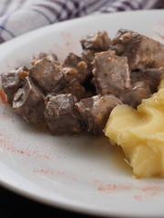 Braised beef in sauce and mashed potatoes on a white plate