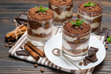 Classic tiramisu dessert in a glass on wooden background