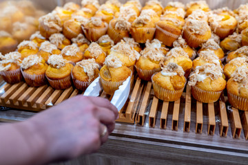 Hand picking meat floss muffin by clamp at pastry shop