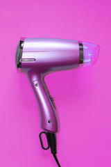 Pink Hair dryer isolated on pink background.Hairdressing tools.Fashion red hair dryer and hairbrushes. Hair tool set on a colorful table. Barber set . Professional hairdresser tools.