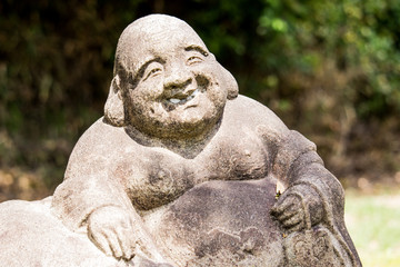 Fototapeta na wymiar The close up image of Jizo (Burai / Hotei) by unknown sculptor on the street, Nagoya, Japan. In Japan, there are many old Jizo statues which were made in long ages ago.