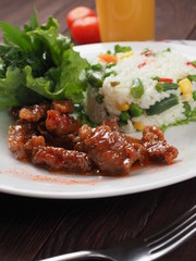 Roasted meat, white rice and vegetables on wooden table