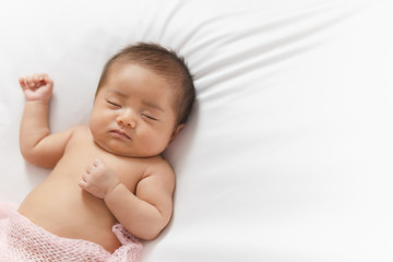 Adorable asian newborn baby in pink wrap sleeping on white blanket background.