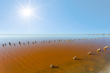 red saline lake with remains of an old constructions under a sparkle sun
