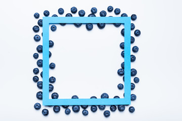 Fresh blueberries framed with square paper cut, top view