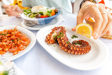 Close-up of a woman eating delicious seafood - shrimp and octopus grilled and vegetable salad. The concept of Mediterranean cuisine and healthy food