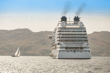 A small yacht and a large cruise ship are dangerously close at sea. The concept of a journey or...