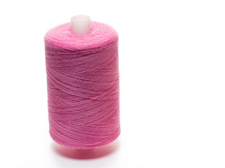 Pink spool of thread in a vertical position on a white background