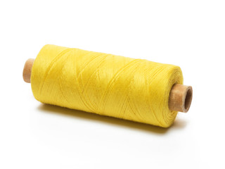 Yellow spool of thread in a horizontal position on a white background