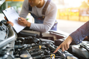 Professional mechanic holding a clipboard of service and check engine in garage. Repair service.