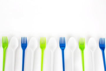Bright color disposable plastic forks and spoons isolated on white background. Ecology problem. Top view. Free space for text.	