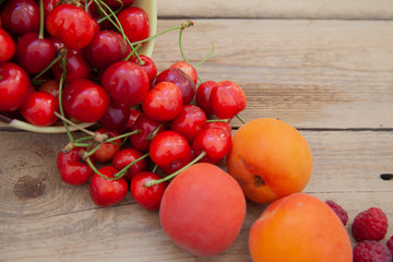 scattered berries from a plate of raspberry cherries apricots on a wooden table