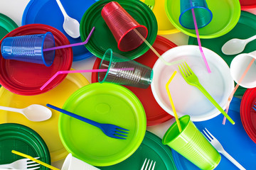 Bright color disposable plastic tableware  background. Picnic set. Ecology problem. Top view.	