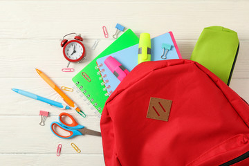 Flat lay composition with backpack and school supplies on white wooden background