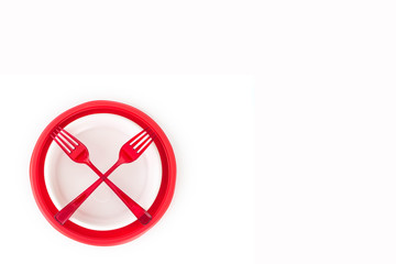 Bright red disposable plastic plates isolated on white background and crossed red forks. Ecology problem. No plastic concept. Top view. Free space for text.