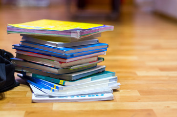 Stack of Textbooks and Black Backpack on Wooden Floor. Education, School Holidays, Back to School Concept. Copy Space.