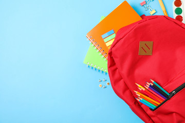 Flat lay composition with backpack and school supplies on color background