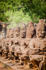 Stone carved warriors flank the side of a bridge at Angkor Wat, Cambodia (selective focus)
