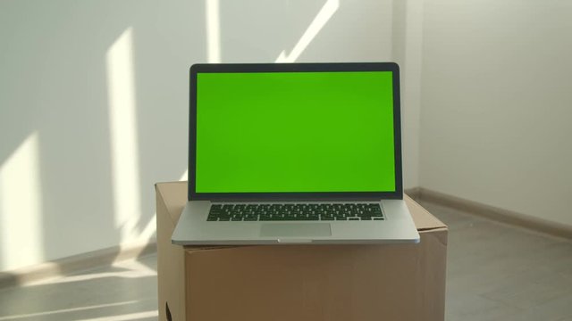 Closeup shoot of laptop with green screen laying on the box in the office indoors