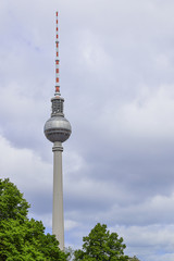 Naklejka premium Berlin Fernsehturm with clouds and trees