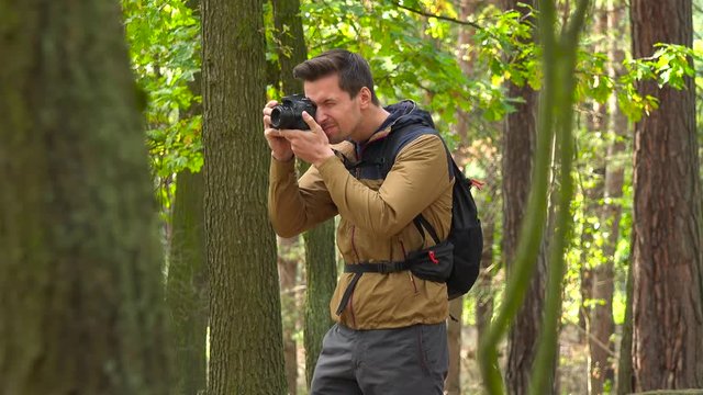 A hiker takes pictures with a camera in a forest