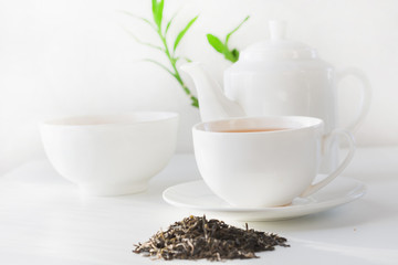 Still life cup of green tea with green tea dry leaves on white. Teatime.