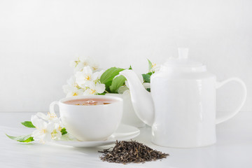 Cup of green jasmin tea white jasmine flowers, teapot. Teatime.