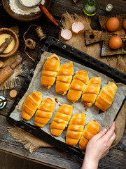 Overhead shot of delicious homemade baked sausages rolled in dough on baking tray on wooden rustic table