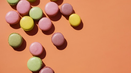 An elevated view of yellow; pink and green macaroons on colored backdrop