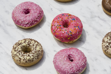 Different type of donuts on marble textured backdrop
