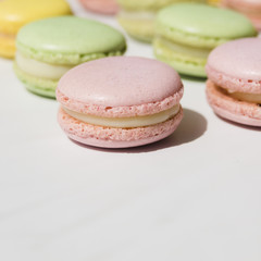 Fototapeta na wymiar Green and pink whipped cream macaroons on white backdrop