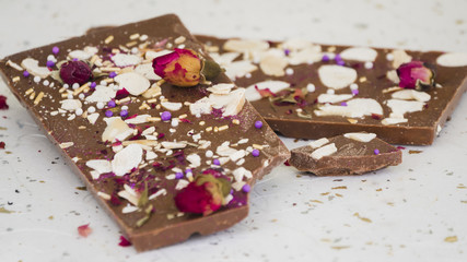 Dried fruits and rose petals on eaten chocolate bar