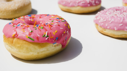 Pink donuts with colorful sprinkles on white background