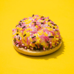 Donut wrapped with sprinkles on yellow background
