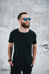 Handsome hipster man with beard wearing black blank t-shirt with space for your logo or design.