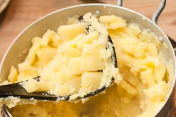 Chopping mashed potatoes with a special press. Hot and delicious dish of homemade potatoes.