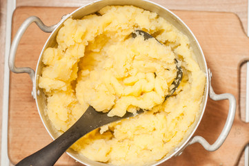 Chopping mashed potatoes with a special press. Hot and delicious dish of homemade potatoes.