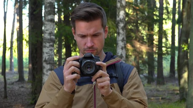 A young handsome hiker looks at the pictures on his camera - closeup
