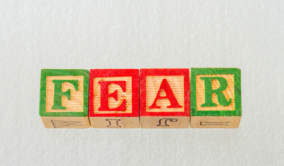 The term fear visually displayed on a clear background using colorful wooden blocks image in landscape format