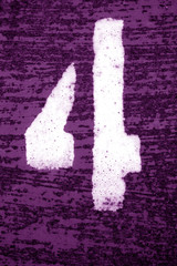 Number 4 in stencil on grungy metal wall in purple tone.