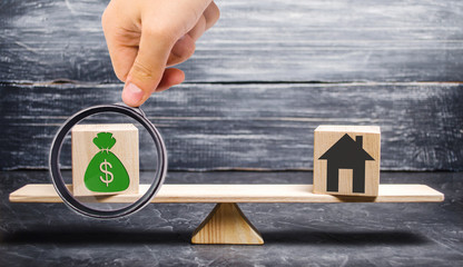 House with money on the scales and wooden blocks. The concept of real estate purchase. Sale of...
