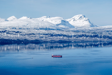 Single freight ship and tug boat in Norway mountain fjord