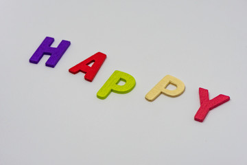 The HAPPY text from colorful wooden letters is on white background, learning alphabet, Sensitive focus.