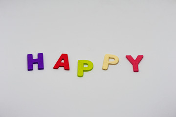 The HAPPY text from colorful wooden letters is on white background, learning alphabet, Sensitive focus.
