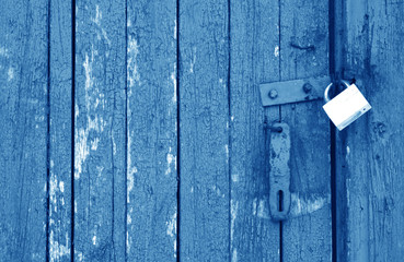 Old padlock on wooden gate in navy blue tone.