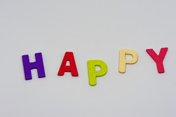 The HAPPY text from colorful wooden letters is on white background, learning alphabet, Sensitive focus.