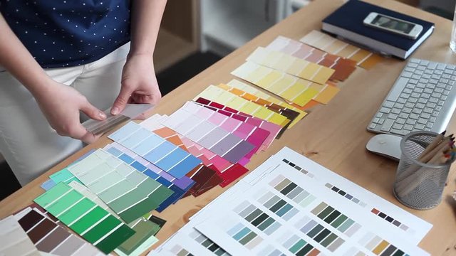 Young woman designer chooses from color palette and fabric samples the best for her client