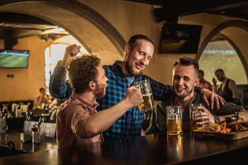 Friends drinking draft beer and watching tv in a pub