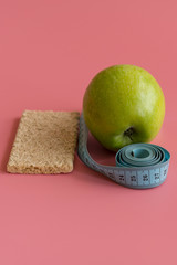 Dieting Concept Green Apple and waist line on a pink background. vertical photo.